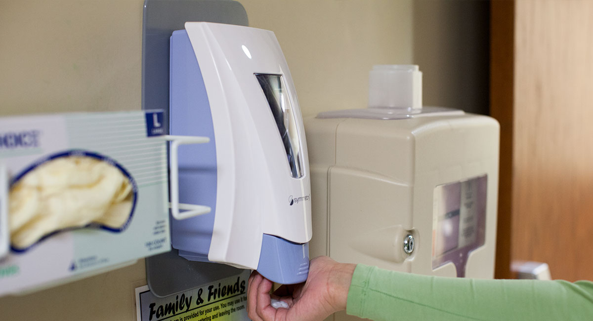 Nurses hands using a Symmetry Stealth Empathy dispenser inside of a room