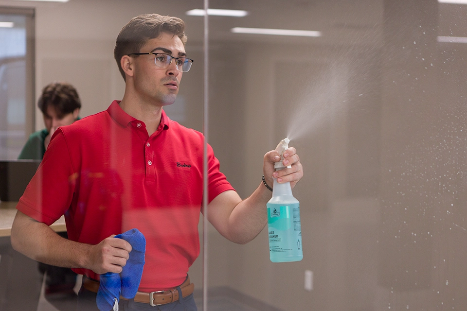 Man spraying glass with Buckeye Eco Pods Glass Cleaner Spray Bottle